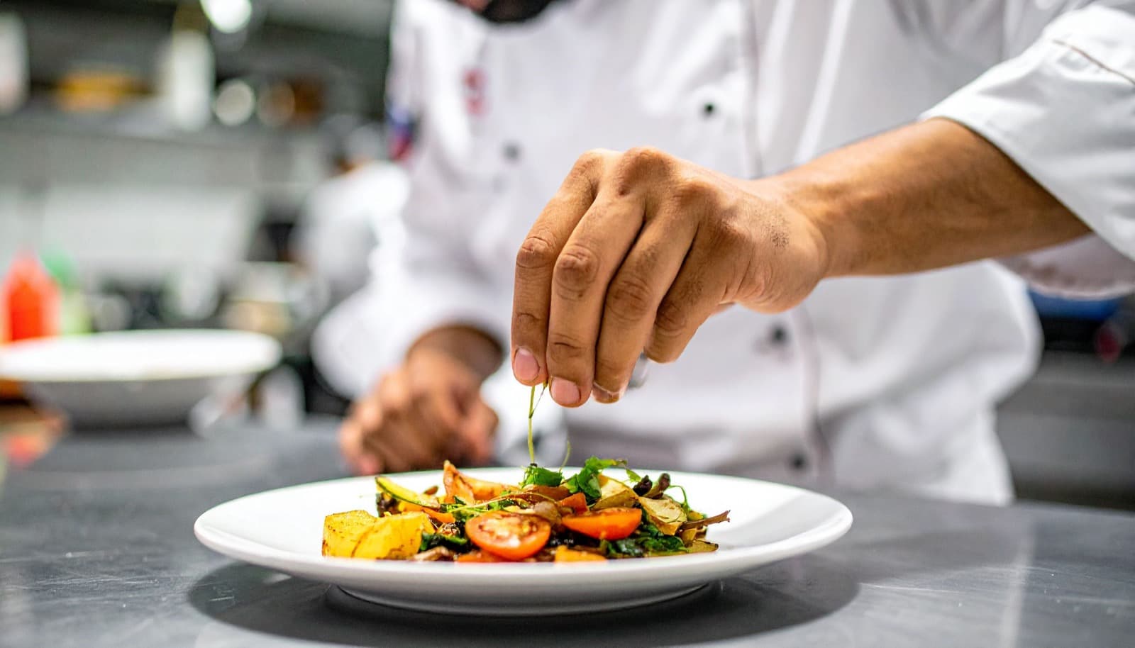A chef plating a dish in a restaurant kitchen